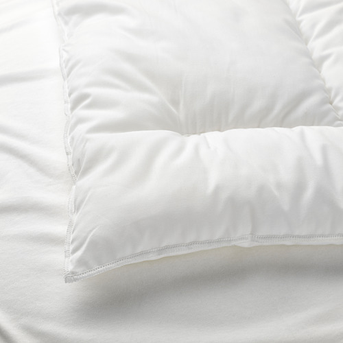 Primer plano de una almohada blanca de felpa sobre ropa de cama blanca y fresca, que muestra materiales y costuras de calidad.