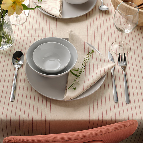 Mesa con platos blancos, cubiertos y mantel a rayas, con guarnición verde en servilletas.