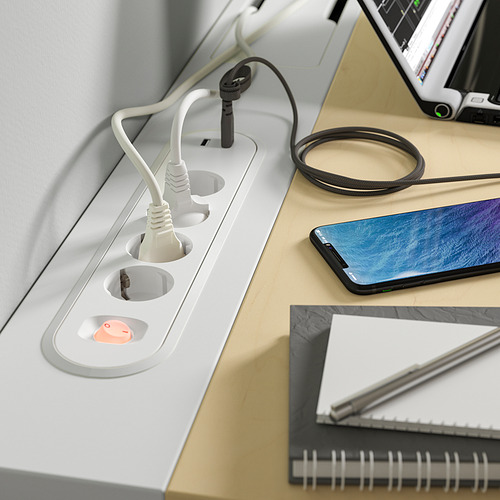 Un escritorio blanco con tomas de corriente incorporadas y una bandeja de administración de cables, que sostiene un teléfono inteligente, una computadora portátil y un bolígrafo.