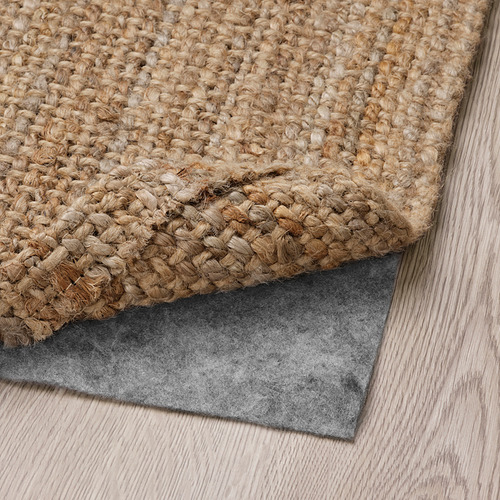 Alfombra de yute con base antideslizante sobre suelo de madera, equilibrando comodidad y seguridad.