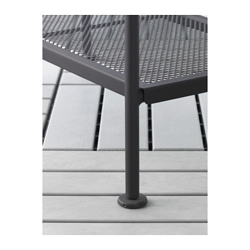 Mueble de exterior de metal negro con patas ajustables y estante perforado, sobre cubierta de madera gris.