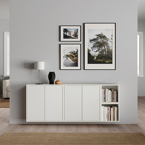 Sala de estar moderna con piso de madera de color claro, unidad de almacenamiento EKET blanca y tres fotos de la naturaleza enmarcadas en una pared gris.