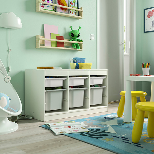 Sala de juegos con mueble de almacenaje TROFAST, verde claro, de madera, bajo, cubos para almacenaje, cerca de sillas amarillas y puerta abierta.