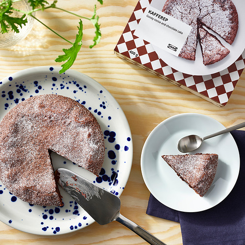 La imagen muestra un pastel de chocolate pegajoso con la etiqueta KAFFEREP, mitad servido en un plato y mitad en su empaque, con una rebanada en un plato separado listo para comer.
