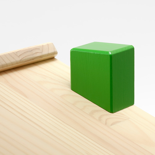 Un bloque cuadrado verde se encuentra sobre una mesa de madera clara, mostrando artesanía de calidad con superficies lisas y líneas limpias.