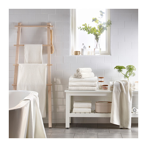 Baño ordenado con toallas blancas, estante de madera, planta y decoración.