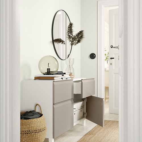 Modern white BESTÅ sideboard with open doors revealing storage compartments and shelves, topped with decorative items.