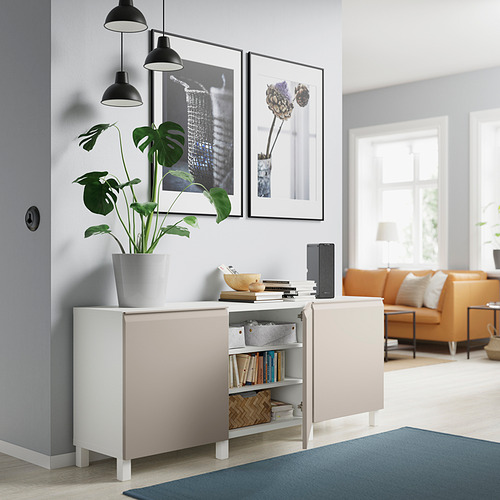 Habitación moderna con aparador blanco BESTÅ, planta de interior, sofá naranja, lámparas, libros y arte enmarcado.