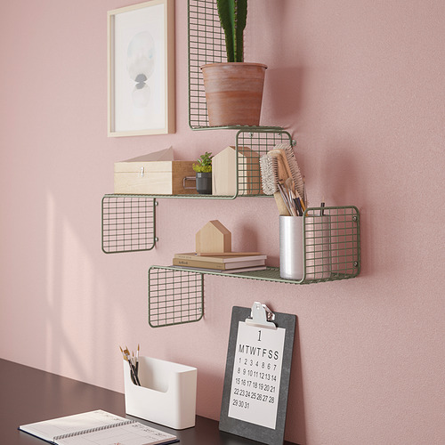 Estantes de rejilla montados en la pared con varios artículos: una planta en maceta, pinceles, libros y un portapapeles con un calendario. Organización personalizada en pared rosa.