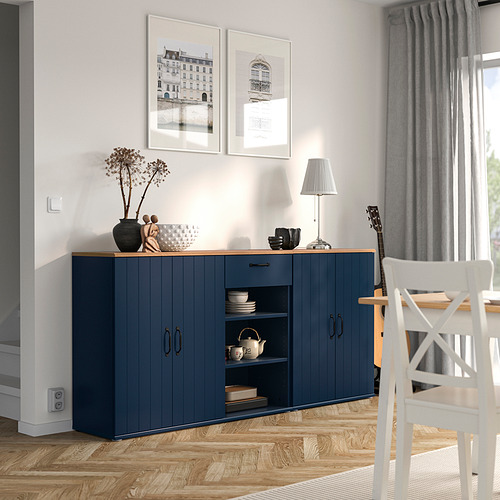 Comedor moderno con aparador azul SKRUVBY, silla blanca, piso de madera, cortinas grises, fotos y lámpara.