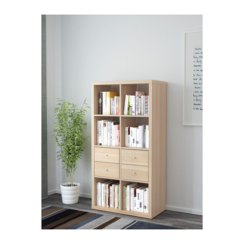 Light wood bookshelf with drawers and books.