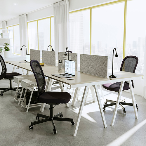 Moderno espacio de oficina con múltiples escritorios blancos ROTTEN, sillas negras, computadoras portátiles y divisores. Habitación amplia y luminosa con grandes ventanales.