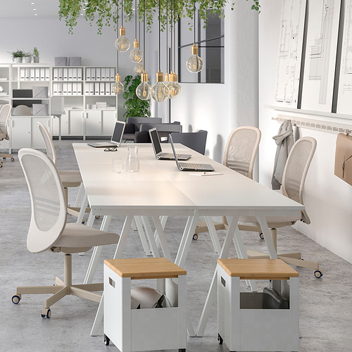 Oficina moderna con escritorios TROTTEN blancos y sillas flintan beige, con elegantes lámparas colgantes y decoraciones frondosas.