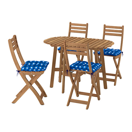 Mesa exterior de madera y cuatro sillas. Las sillas tienen cojines de lunares azules. Conjunto plegable, acabado natural.