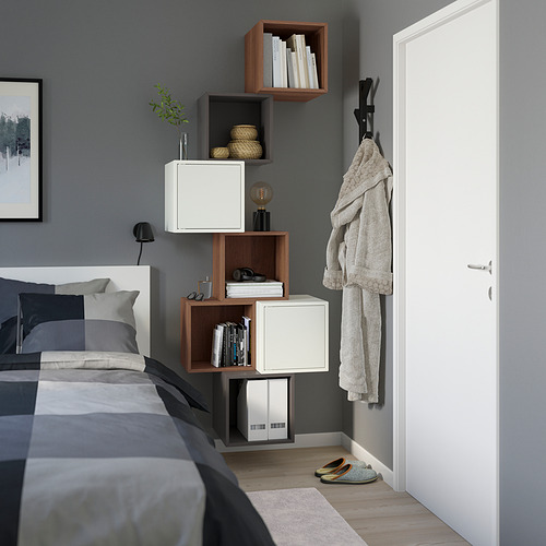 Dormitorio moderno con estantes EKET, que mezcla almacenamiento abierto y cerrado, en lo alto de la pared. La ropa de cama gris completa el look minimalista.