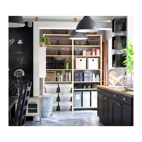 Cocina moderna con estanterías, cestas y contenedores IVAR en madera clara, lámparas negras colgantes y una pared de pizarra.