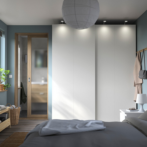 Dormitorio moderno con armario blanco PAX, ropa de cama gris, iluminación acogedora y detalles en madera.