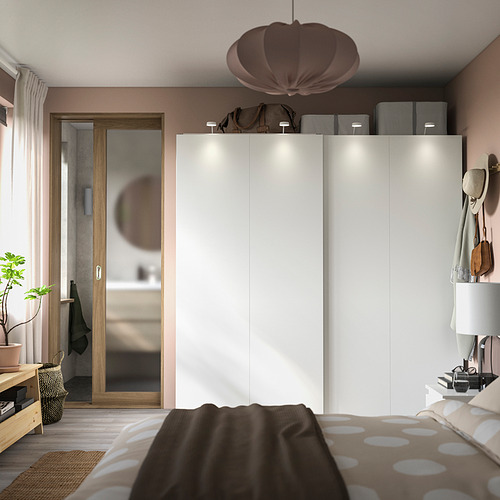Dormitorio moderno con grandes armarios correderos blancos HASVIK, decoración marrón suave y ropa de cama de lunares.