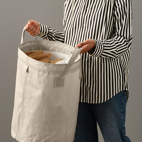 Persona sosteniendo una bolsa clasificadora DIMPA con asa, llena de artículos. La bolsa tiene un divisor en su interior.