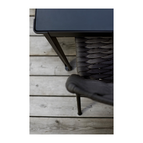 Primer plano de mesa y silla de exterior moderna de metal negro, negro con cuerda gris oscuro.