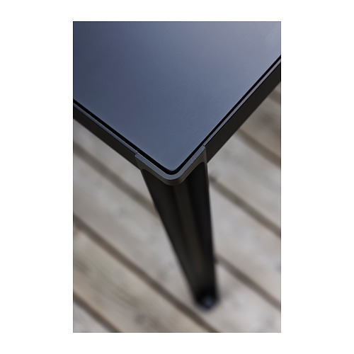 Mesa de exterior gris con elegantes patas de metal negro y superficie superior lisa.