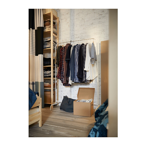 Habitación con suelo de madera, perchero MULIG con ropa, caja, bolsa, cama parcial.