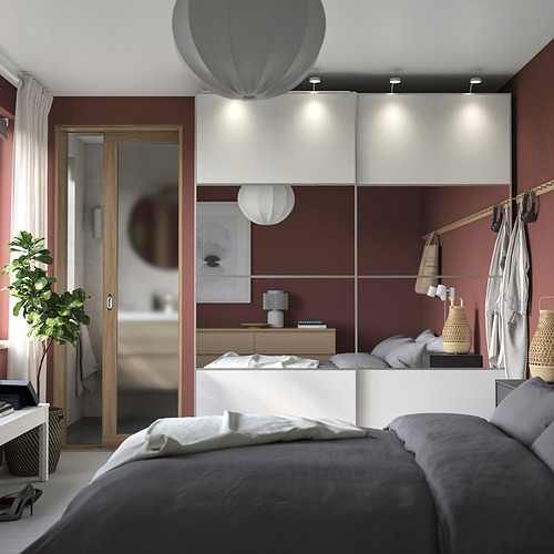 Dormitorio moderno de color rojo con cama gris, lámpara de mesa, armario con espejos, luces colgantes y planta.
