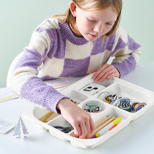 Niña organizando materiales de arte en una bandeja de plástico dividida, que es parte del sistema de almacenamiento TROFAST para niños.