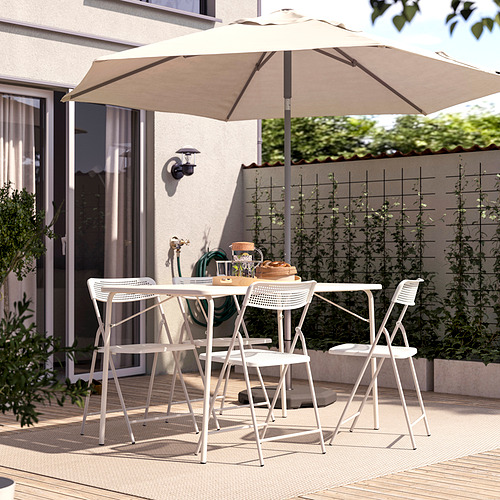 Patio exterior con sombrilla beige TORPARÖ y mesa/sillas de metal blanco. Configuración compacta y elegante con un diseño moderno, ideal para espacios pequeños.