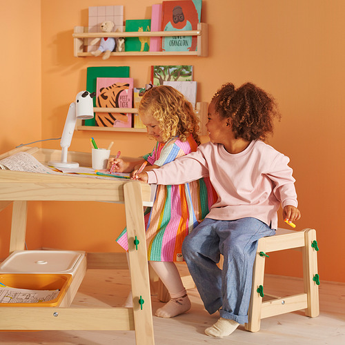 Dos niños sentados en un banco FLISAT de altura ajustable, dibujando y colaborando. Efectivo para diferentes edades, construcción robusta de pino.