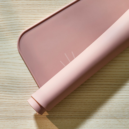 Mantel individual de silicona de color rosa pálido con esquinas redondeadas, diseñado para proteger las mesas de derrames y arañazos. Ideal para comidas o manualidades.
