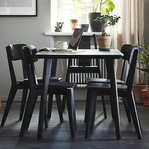 Juego de comedor LISABO negro con mesa y sillas. Computadora portátil, taza y plantas en la mesa. Diseño de inspiración escandinava.