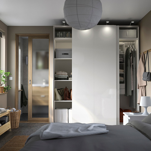 Bedroom with PAX wardrobe, white, modern design, sliding doors, open shelving with clothes, lamp, and gray bed.