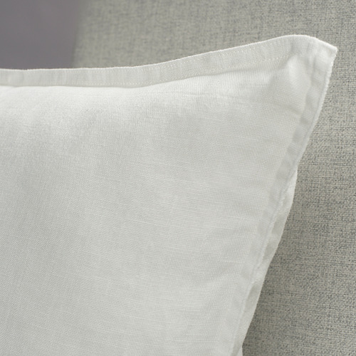 Primer plano de una funda de almohada de lino suave y blanqueado con costuras limpias y una textura sutil, que muestra una artesanía de alta calidad.
