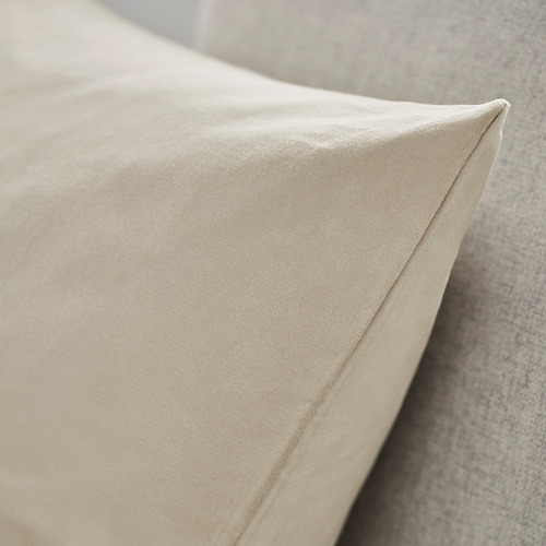 Primer plano de un cojín beige sobre una silla tapizada, luciendo terciopelo de algodón suave y texturizado.