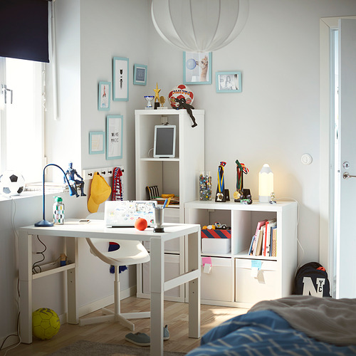 Luminosa habitación para niños con estanterías blancas KALLAX, decoración colorida y artículos deportivos. Un escritorio, una silla y recuerdos personales en la pared.