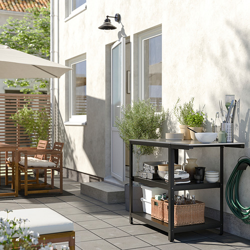 Moderna cocina al aire libre con mesa, platos y plantas GRILLSKÄR al lado de la casa.