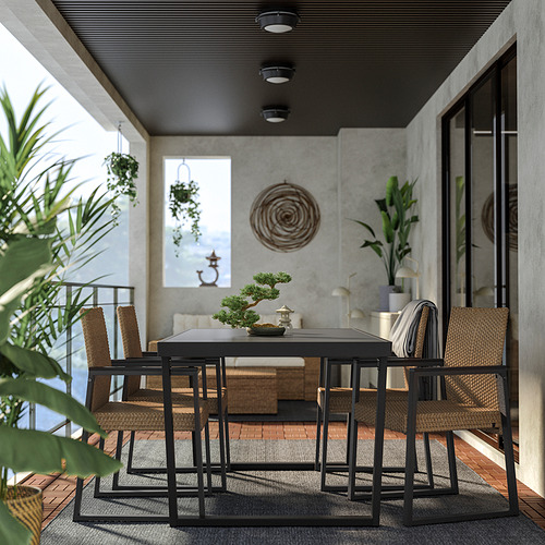Moderno patio al aire libre con mesa de metal negro, sillas tejidas y exuberantes plantas.