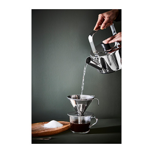 Verter agua en la cafetera sobre la taza sobre una superficie verde, azúcar cerca.