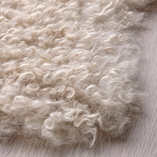 Alfombra blanca suave y rizada sobre suelo de madera; acogedor, texturizado