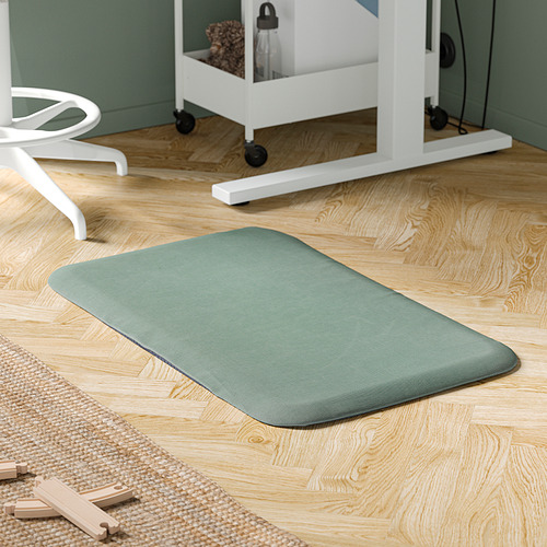 Alfombra de pie FREIVID verde sobre suelo de madera junto a escritorio y silla blancos.