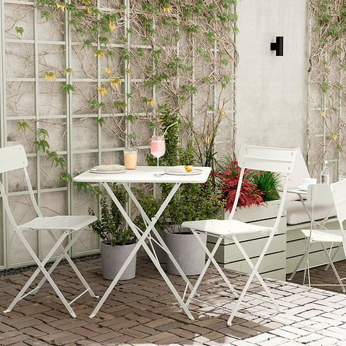 Pequeña configuración de exterior con mesa y sillas plegables blancas, perfecta para balcones.