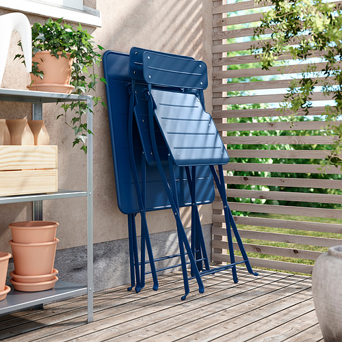 Sillas SUNDSÖ azules apiladas en el balcón con plantas.