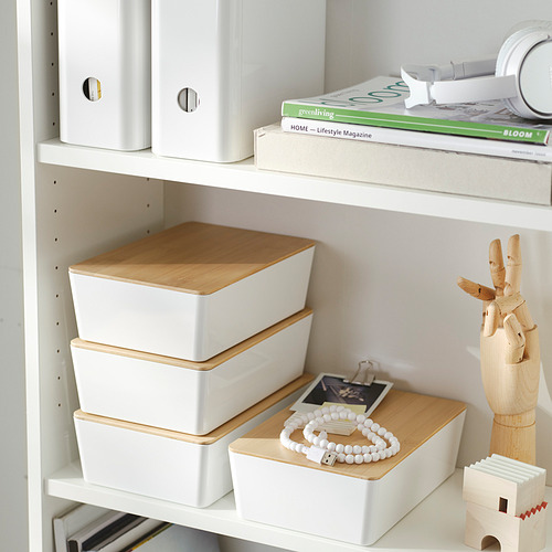 Estantería con cajas de almacenamiento blancas y de madera, revistas y una figura de mano de madera.