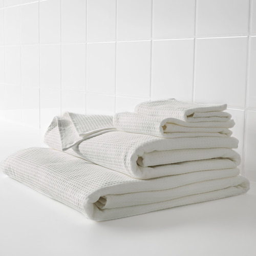 Toallas blancas apiladas, suaves y absorbentes. Textura waffle por un lado, felpa por el otro.