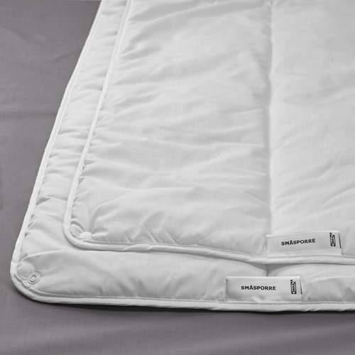 White duvet on gray bed, bordered with recycled material label, showcasing quality and comfort.
