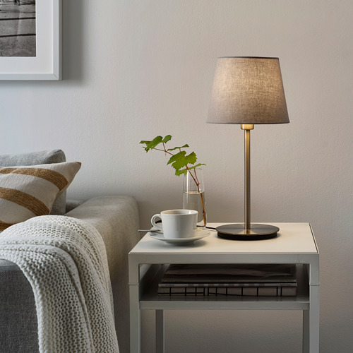 Lámpara de mesa pequeña y moderna, SKAFTET, gris, diseño elegante, cabe al lado del sofá junto a la taza, el jarrón y los libros.