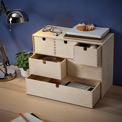 Una unidad de almacenamiento de madera con varios cajones, que almacena varios artículos como una calculadora, artículos de papelería y accesorios.