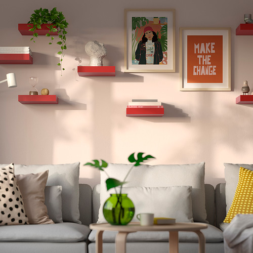 Sala de estar moderna con sofá gris, almohadas de colores y estantes de pared LACK que contienen libros, una planta y decoración.