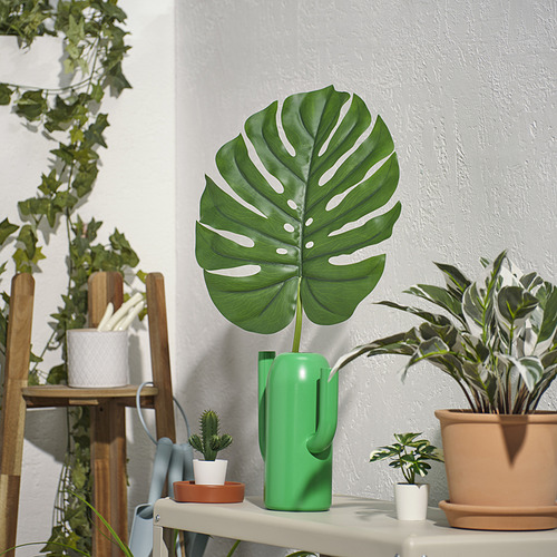 Jarrón con gran hoja verde, más alto que otros, materiales reciclados.